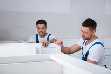 Workers installing new stylish furniture in kitchen