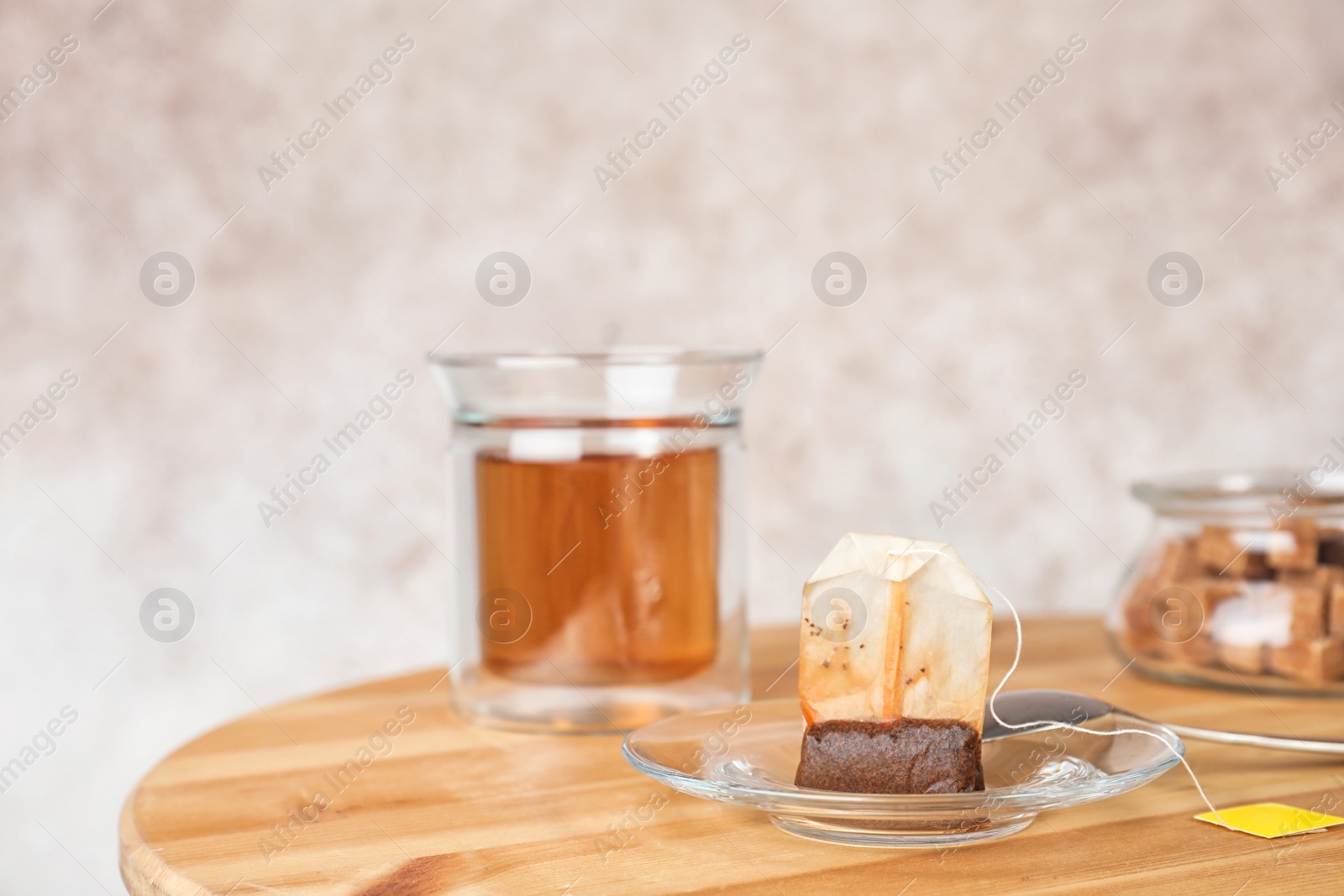 Photo of Saucer, spoon with used teabag and cup on table. Space for text