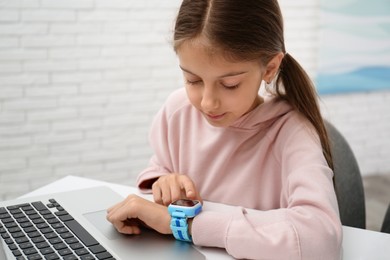 Girl with stylish smart watch at table indoors