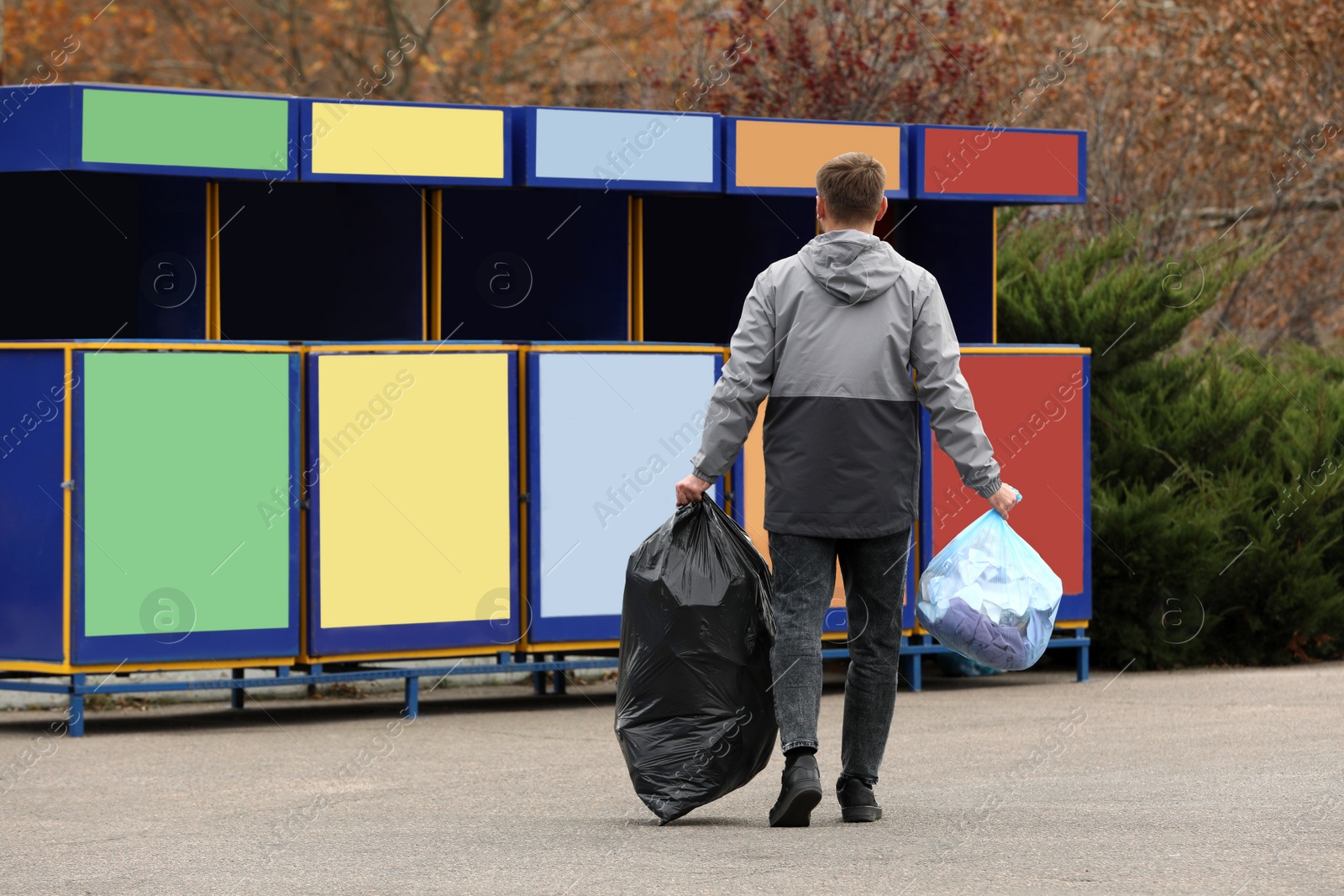 Photo of Man with garbage at recycling point outdoors, back view