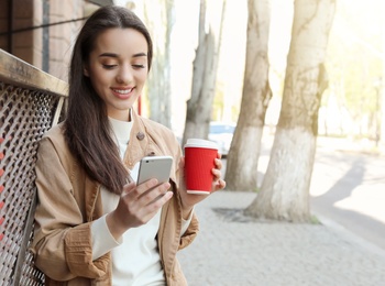 Photo of Young woman using phone outdoors on sunny day