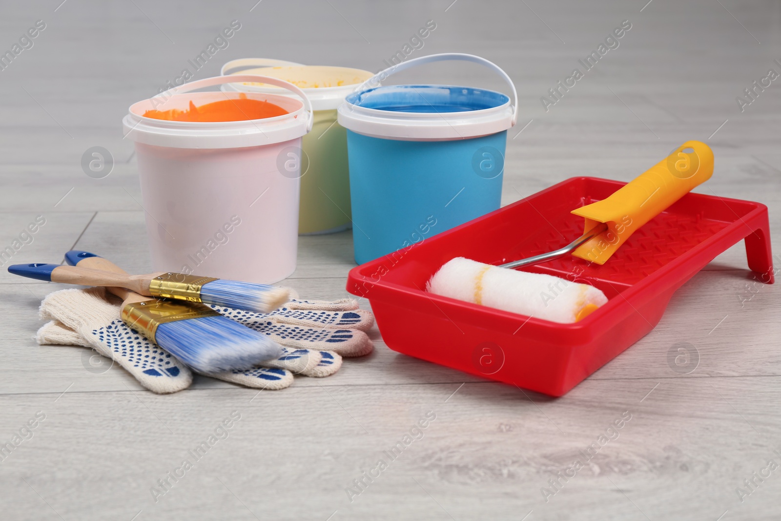 Photo of Buckets of paints and decorator's tools on light wooden background