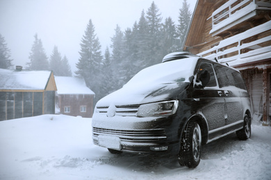 Modern car covered in snow outdoors on winter day