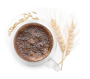 Cup of barley coffee, grains and spikes isolated on white, top view