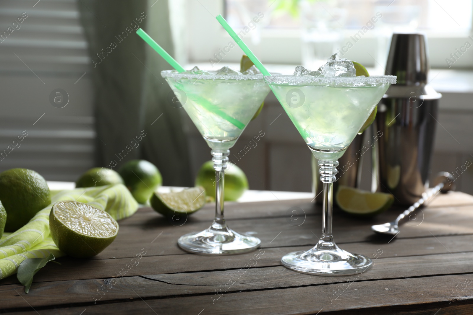 Photo of Delicious Margarita cocktail in glasses and lime on wooden table