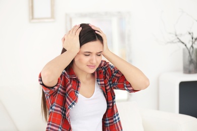 Photo of Young woman suffering from headache at home