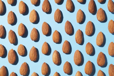 Delicious raw almonds on light blue background, flat lay