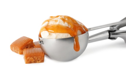 Metal scoop with delicious ice cream and caramel candies on white background