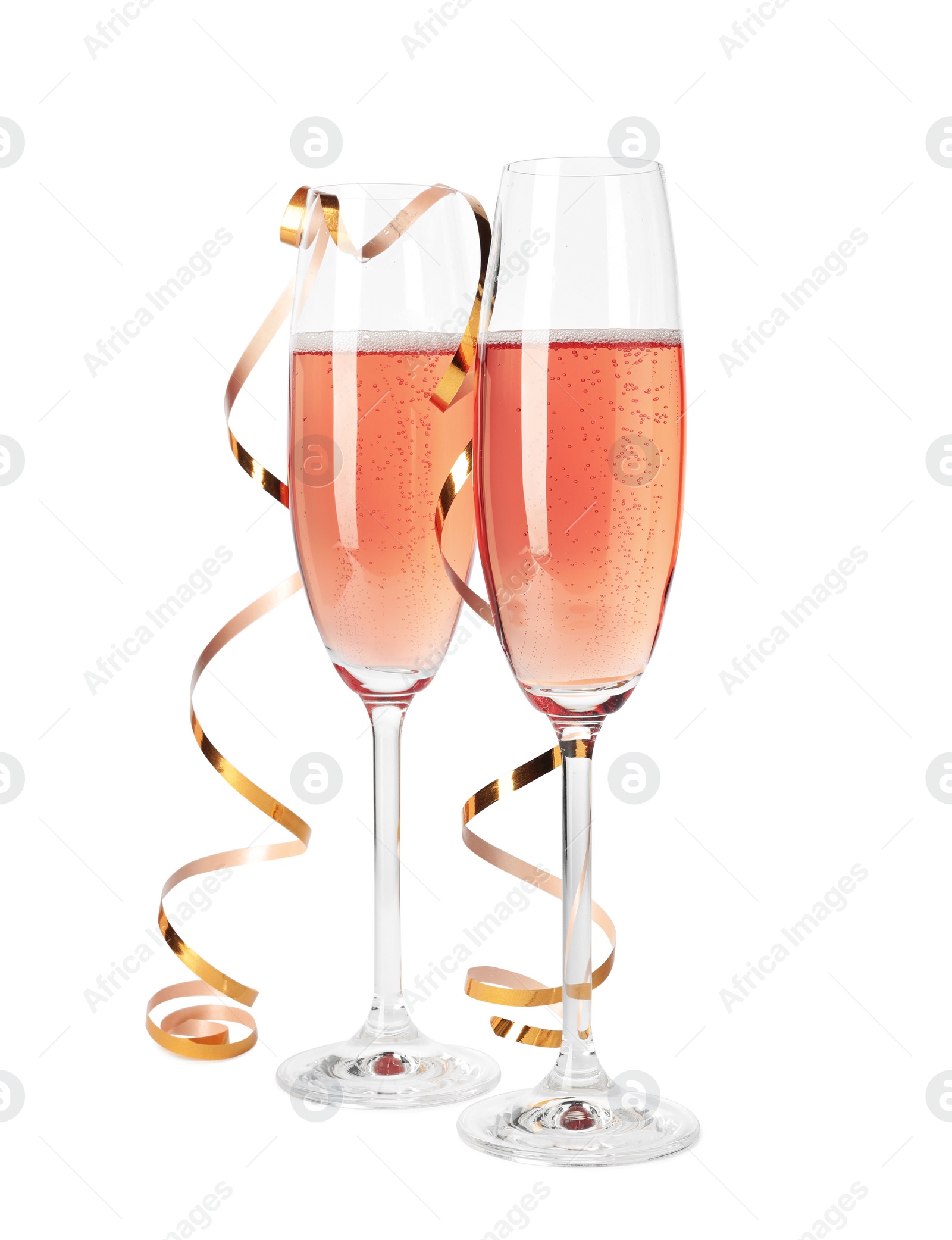 Photo of Glasses of rose champagne with gold streamer isolated on white