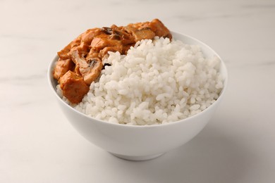Photo of Bowl of delicious rice with meat and mushrooms on white marble table