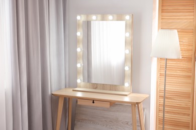 Photo of Beautiful mirror with light bulbs and lamp in makeup room