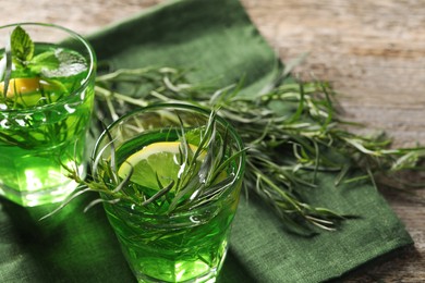 Photo of Glasses of refreshing tarragon drink with lemon slices on wooden table. Space for text