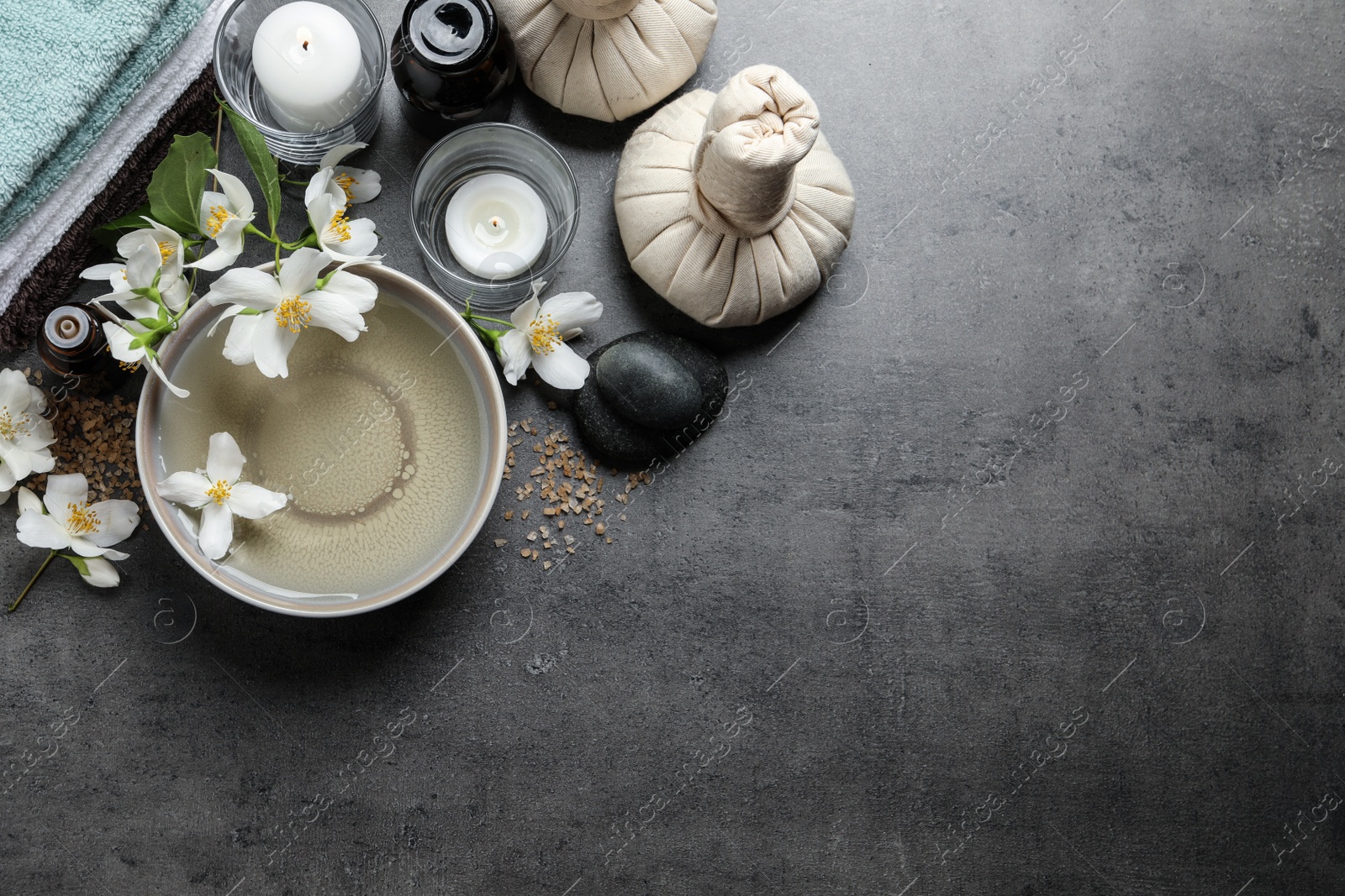 Photo of Beautiful spa composition with jasmine essential oil and fresh flowers on grey table, flat lay. Space for text