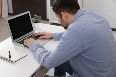 Photo of Man with poor posture working on laptop in office. Symptom of scoliosis