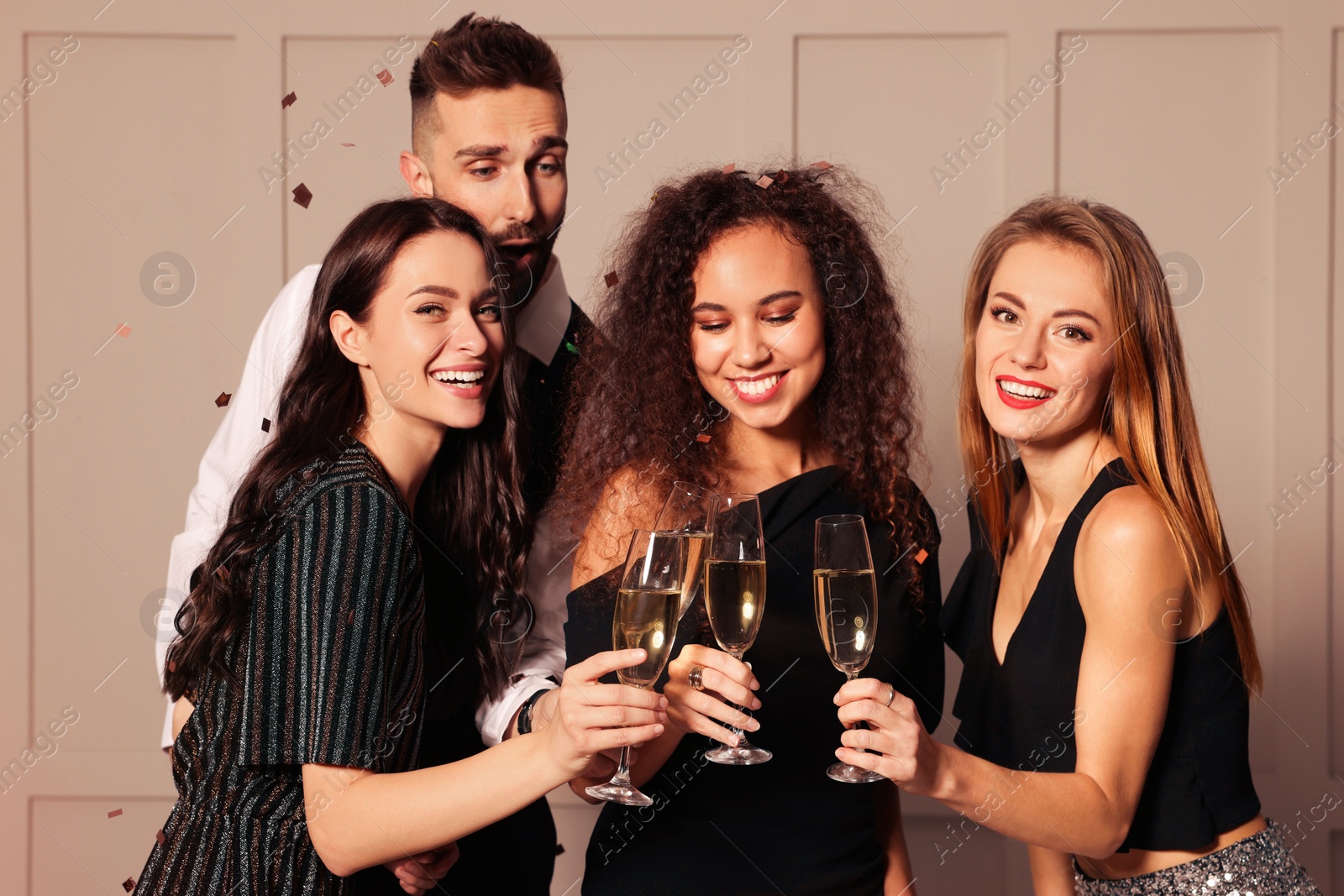 Photo of Happy friends with glasses of sparkling wine celebrating New Year indoors