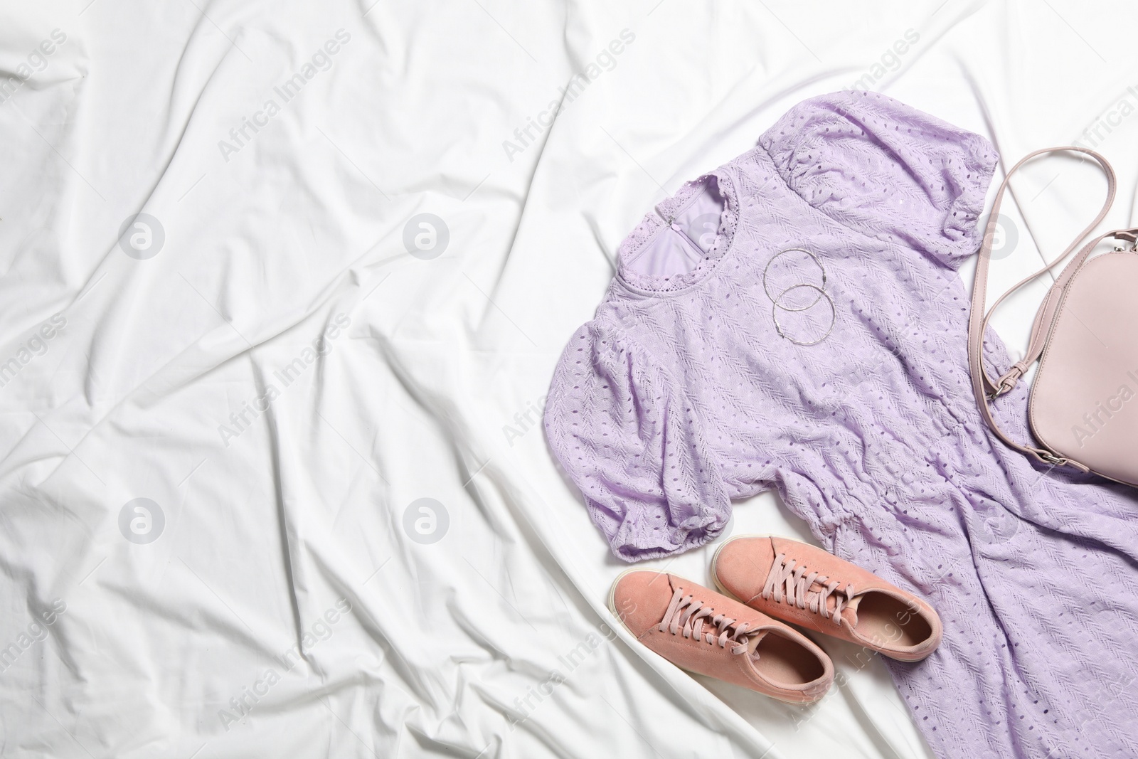 Photo of Flat lay composition with stylish violet dress on white fabric. Space for text