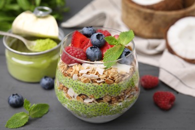 Photo of Tasty oatmeal with chia matcha pudding and berries on black wooden table, closeup. Healthy breakfast