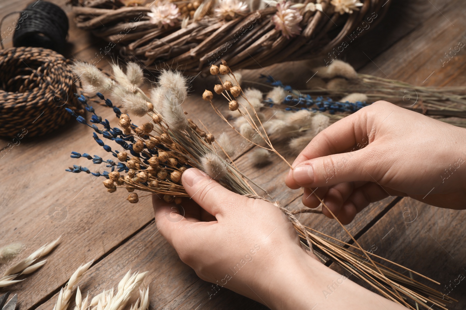 Photo of Florist making bouquet of dried flowers at wooden table, closeup