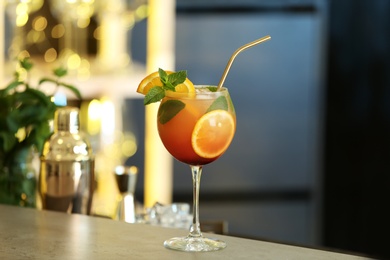 Photo of Fresh alcoholic cocktail with orange and mint on bar counter