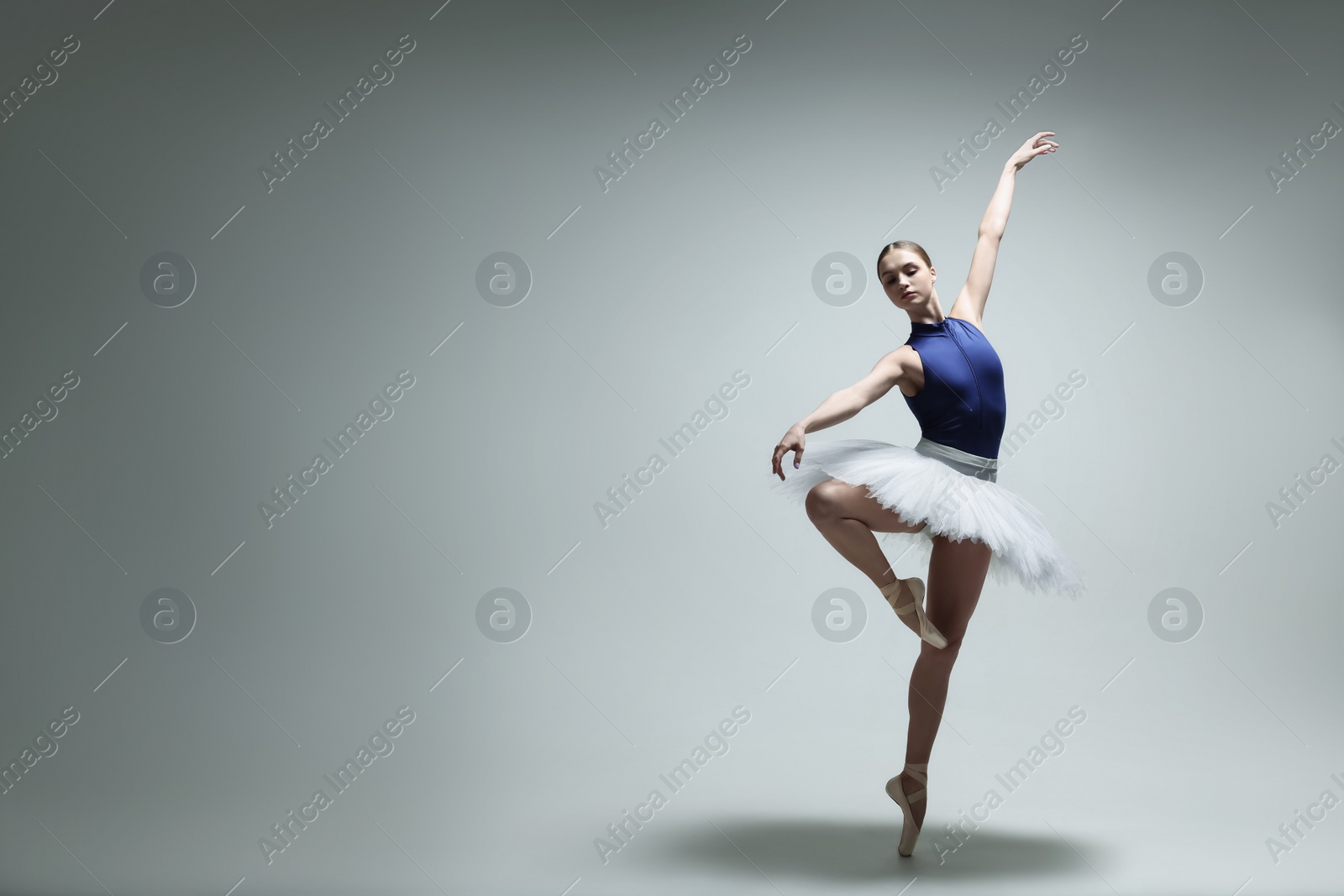 Photo of Young ballerina practicing dance moves on grey background. Space for text