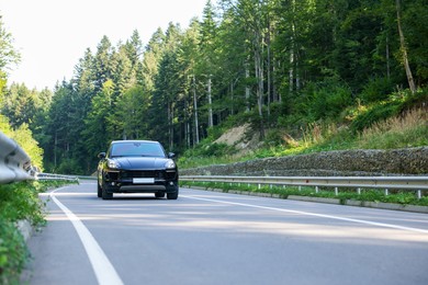 Picturesque view of asphalt road with modern black car