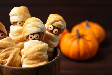 Photo of Spooky sausage mummies for Halloween party served on table, closeup