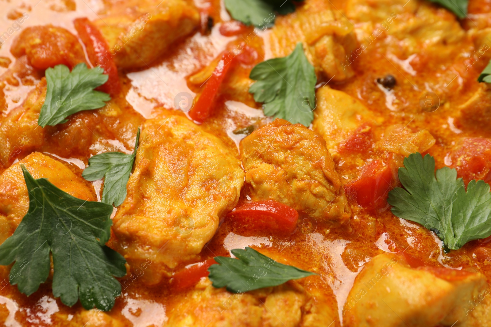 Photo of Delicious chicken curry with parsley as background, closeup