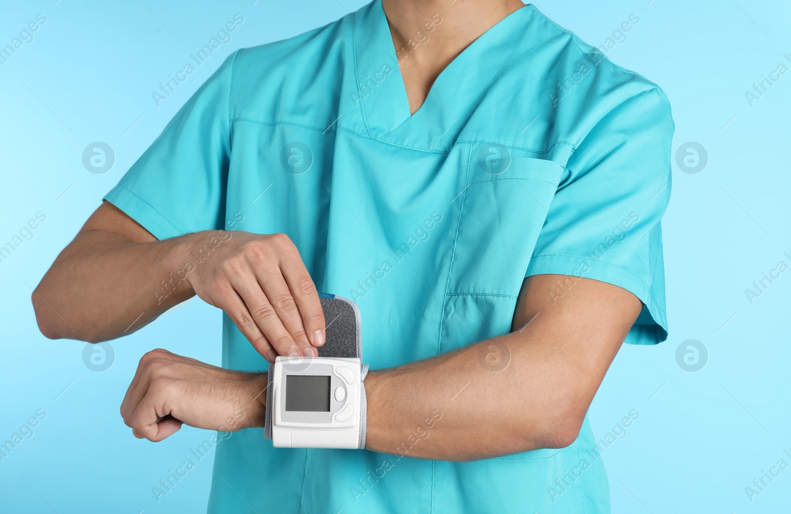 Photo of Male doctor using blood pressure monitor on color background, closeup. Medical object
