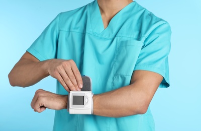 Photo of Male doctor using blood pressure monitor on color background, closeup. Medical object