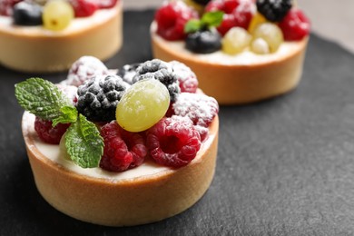 Delicious tartlets with berries on slate board, closeup