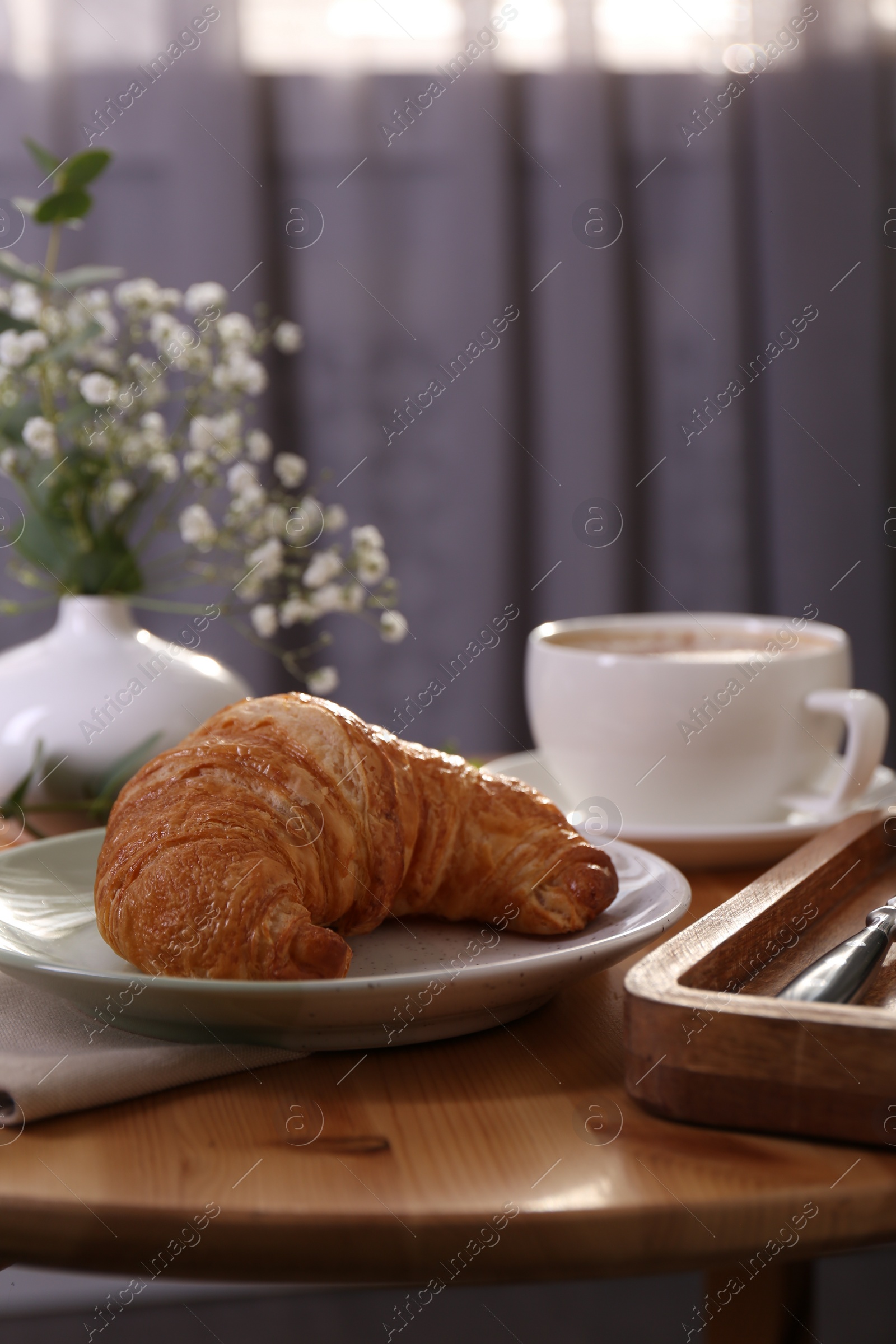 Photo of Tasty croissant served on wooden table indoors