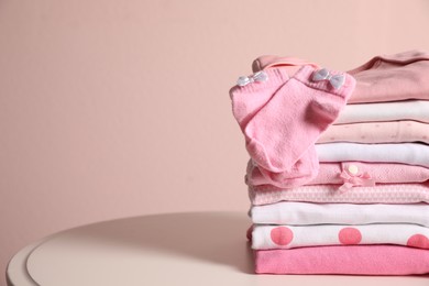 Stack of clean girl's clothes and socks on table. Space for text