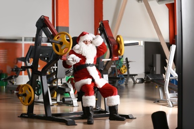 Photo of Authentic Santa Claus resting after exercise in modern gym