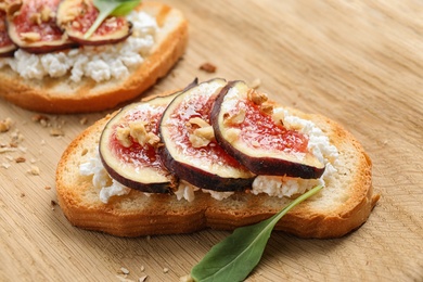 Photo of Bruschettas with cheese and figs on wooden board, closeup