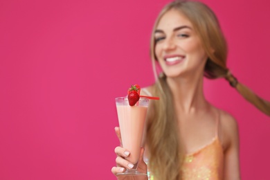 Young woman with glass of delicious milk shake on color background