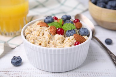Oatmeal served with berries. almonds and mint on white table, closeup