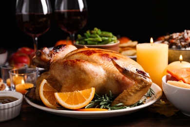 Photo of Traditional Thanksgiving day feast with delicious cooked turkey and other seasonal dishes served on wooden table, closeup