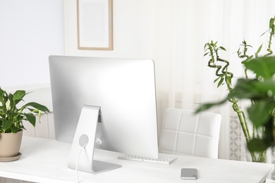 Photo of Office interior with houseplants and computer monitor on table