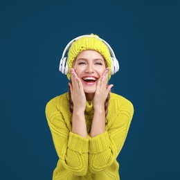 Young woman listening to music with headphones on dark blue background