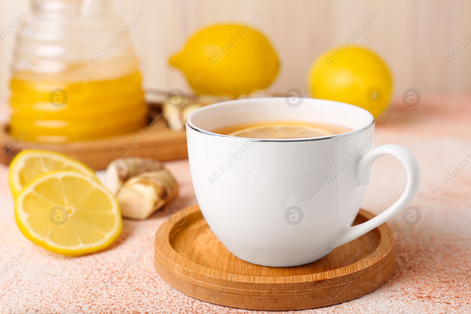 Photo of Tea, honey, lemon and ginger on beige textured table, closeup
