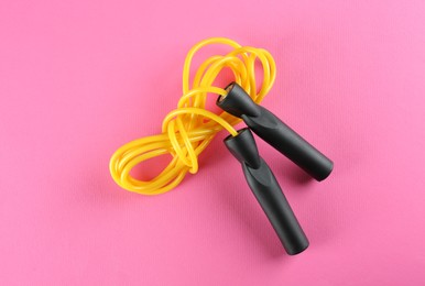 Skipping  rope on pink background, top view. Sports equipment