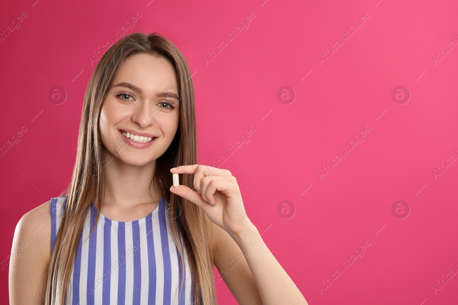 Photo of Young woman with vitamin pill on pink background. Space for text