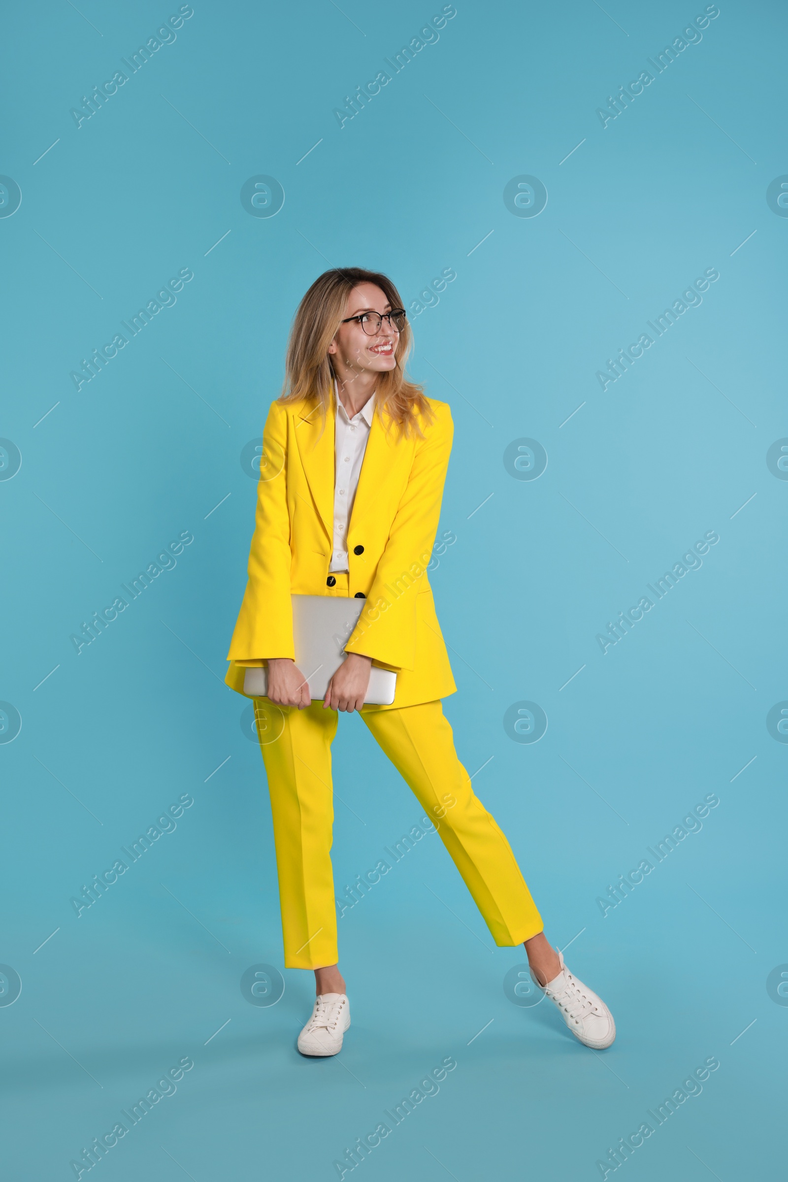 Photo of Young woman with modern laptop on light blue background