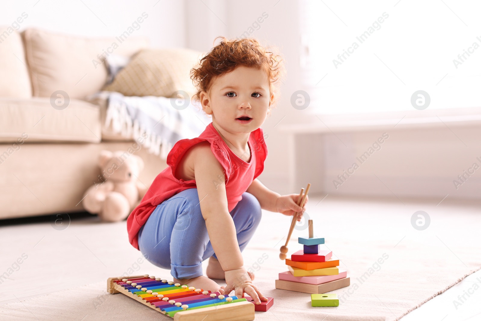 Photo of Cute little child playing with toys on floor at home