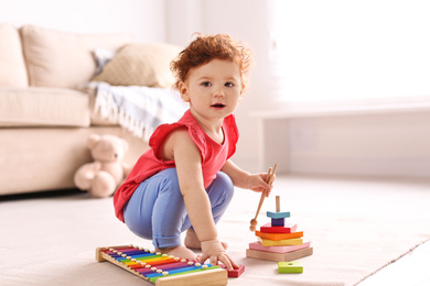 Cute little child playing with toys on floor at home