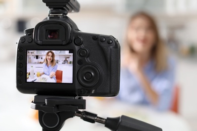 Food blogger recording video in kitchen, focus on camera display. Space for text