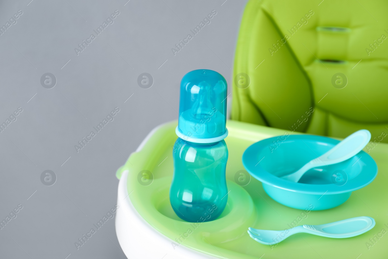 Photo of Set of plastic dishware on white feeding table. Serving baby food