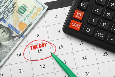 Calendar with date reminder about tax day, pen, money and calculator, top view