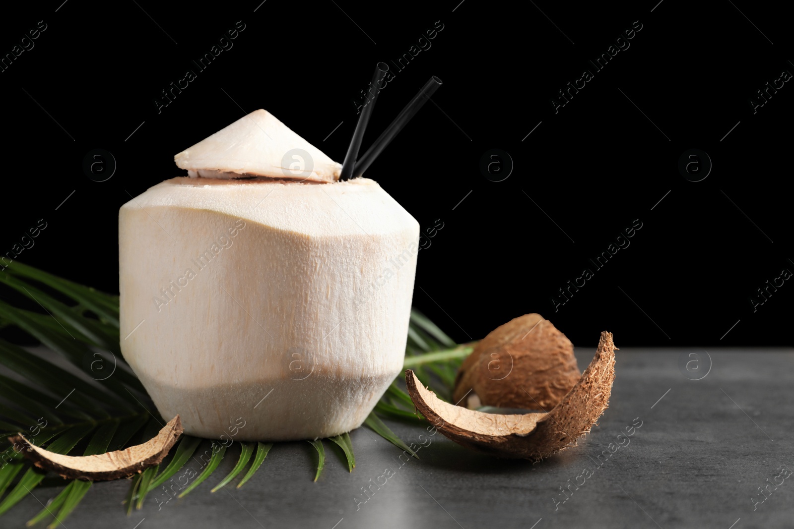 Photo of Fresh coconut drink in nut on table against black background