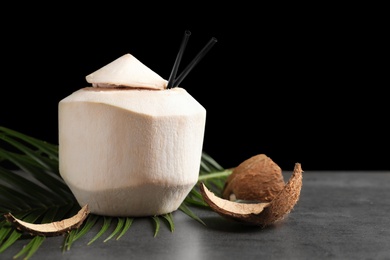 Photo of Fresh coconut drink in nut on table against black background